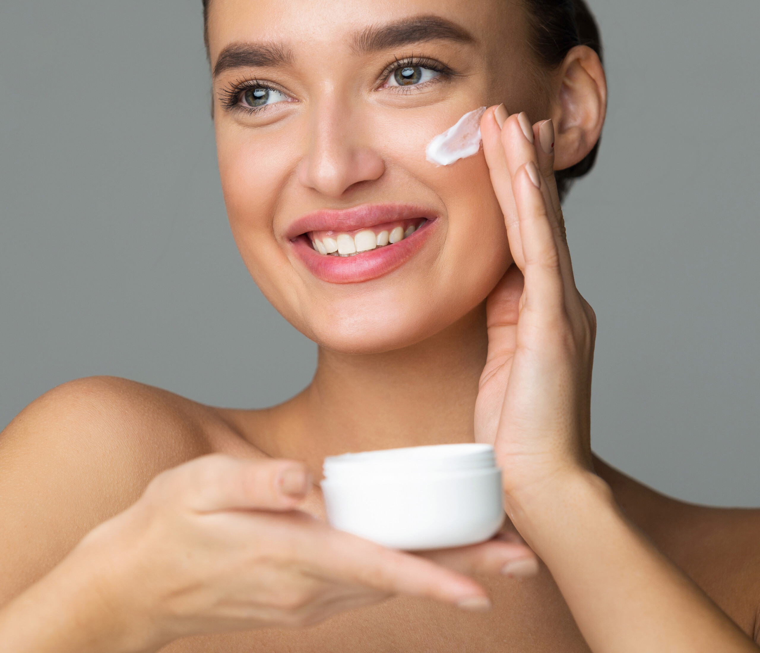 Woman Applying Beauty Eye Contour Wrinkle Cream over Grey Background, Crop